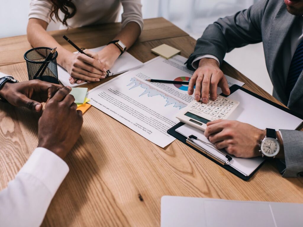 Business meeting with financial documents, charts and calculator on a desk.