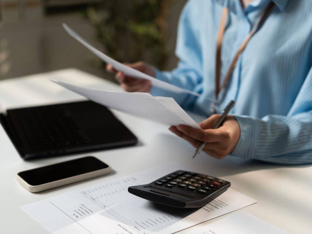 Financial professional analysing documents and calculations during an office review.